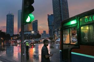 A conductor waits near his bus as a police officer halts the traffic to clear jams during rush hour at the main business district in Jakarta, Indonesia, Friday, Nov. 29, 2013. Jakarta, a megacity with over 9 million inhabitants, is known to have one of the worst traffic jams in Asia. (AP Photo/Dita Alangkara)